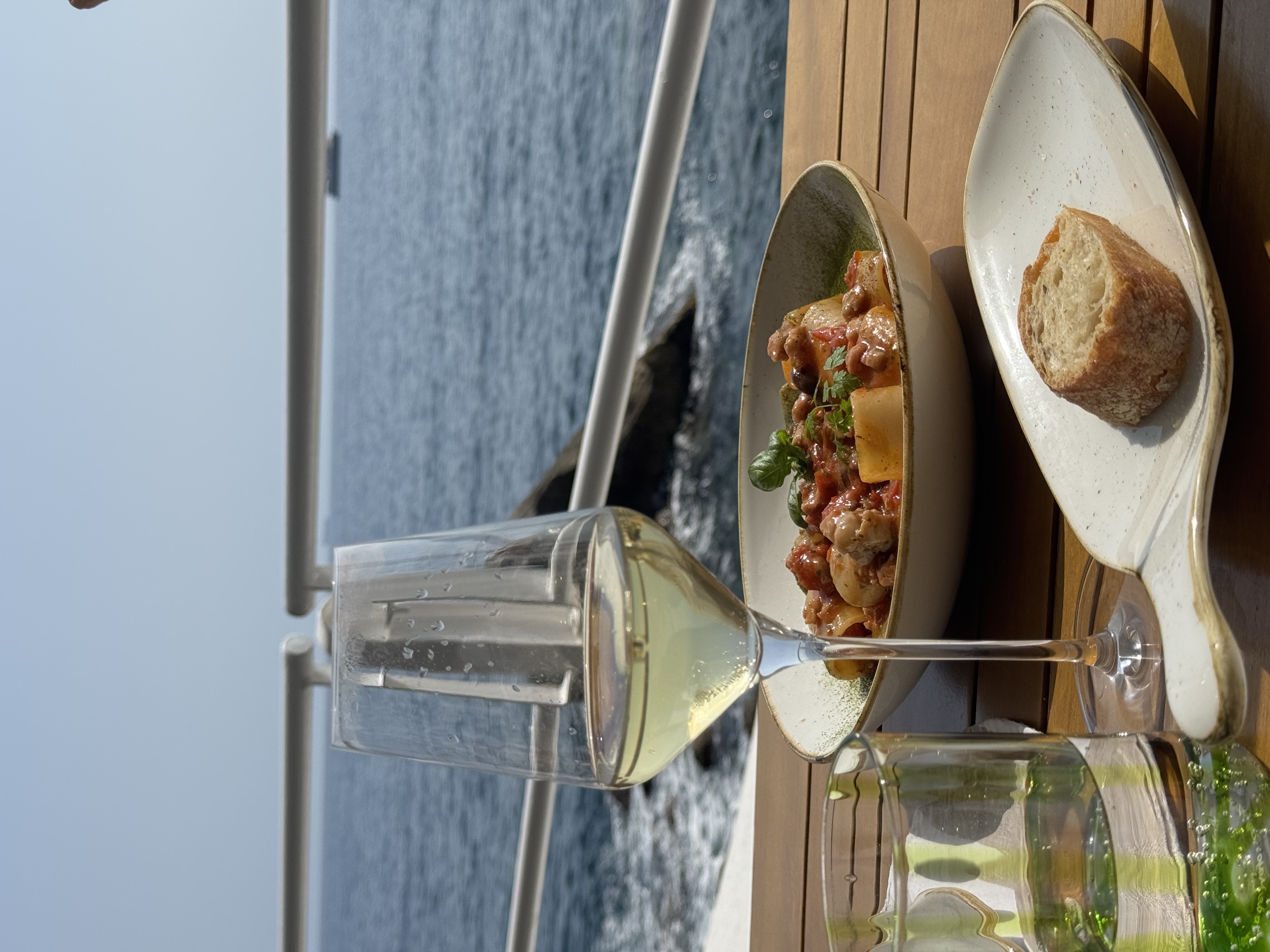 Pasta and white wine at the beach club, sea directly below