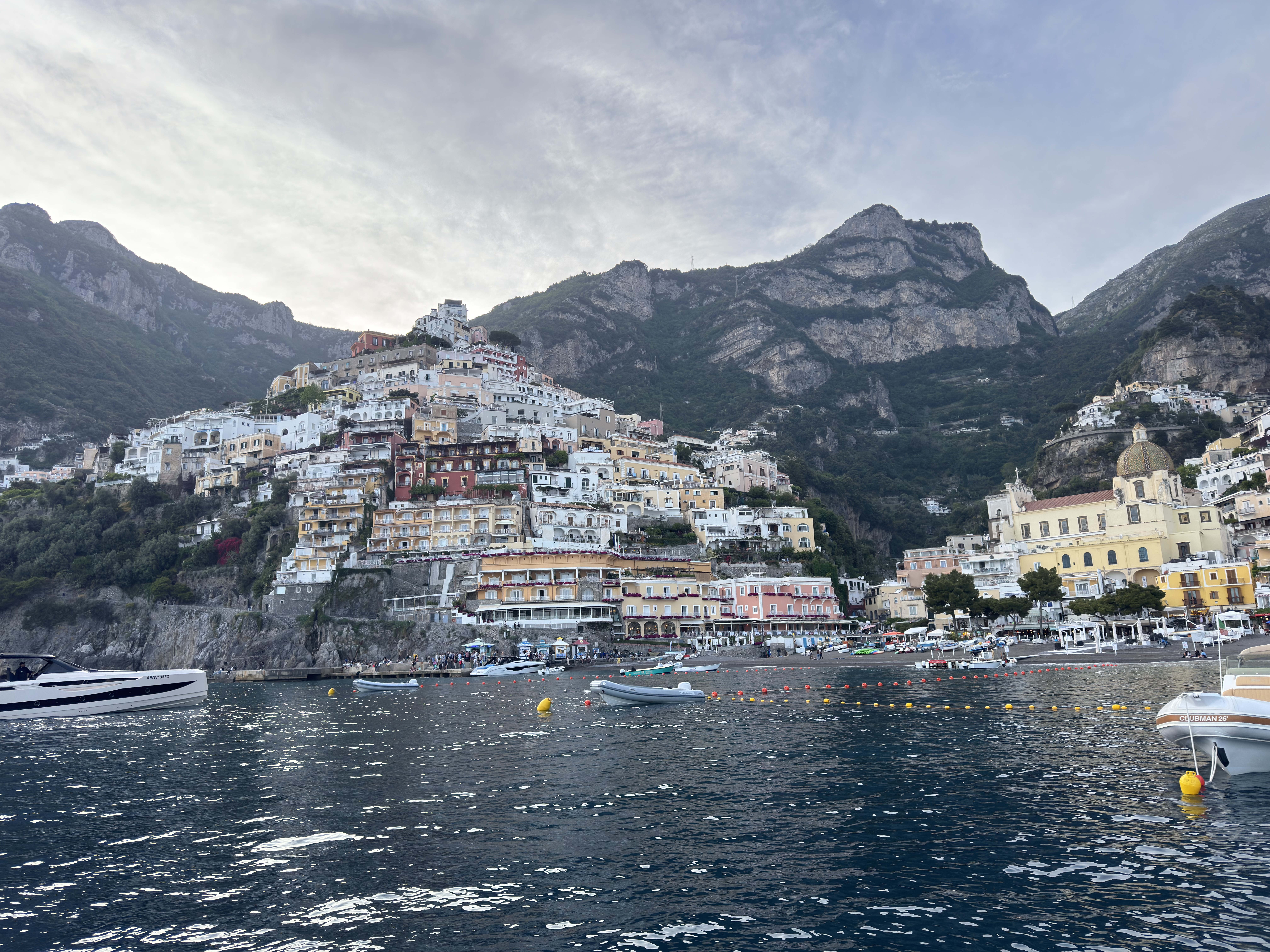 Positano from the water at dusk, buildings stacked up the hillside